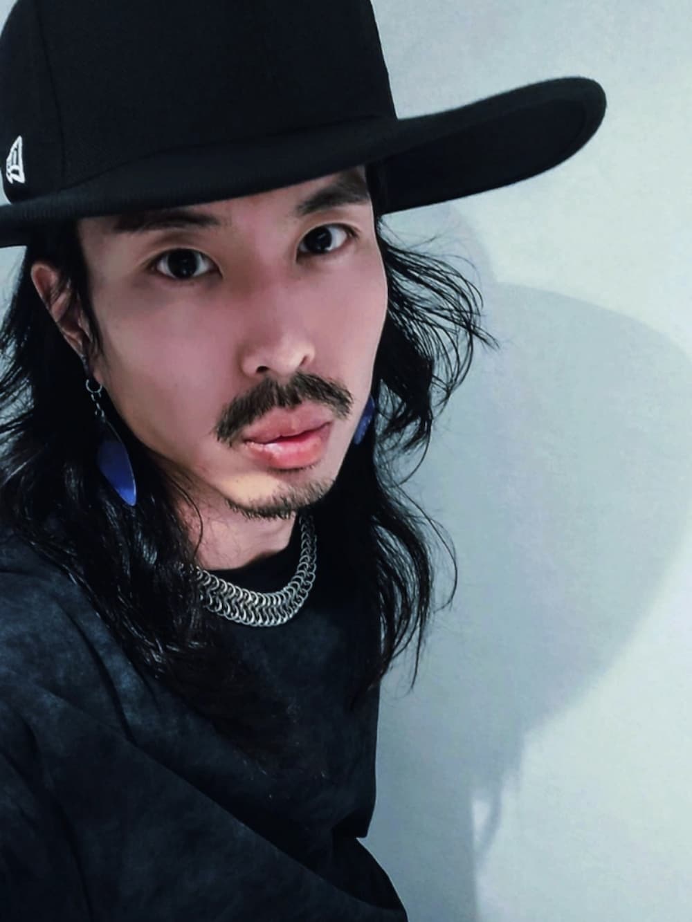 ブラック系のTシャツ/カットソー、ブラック系のハット、シルバー系のイヤリング（片耳用）を着用したメンズの夏コーディネートの2枚目の写真