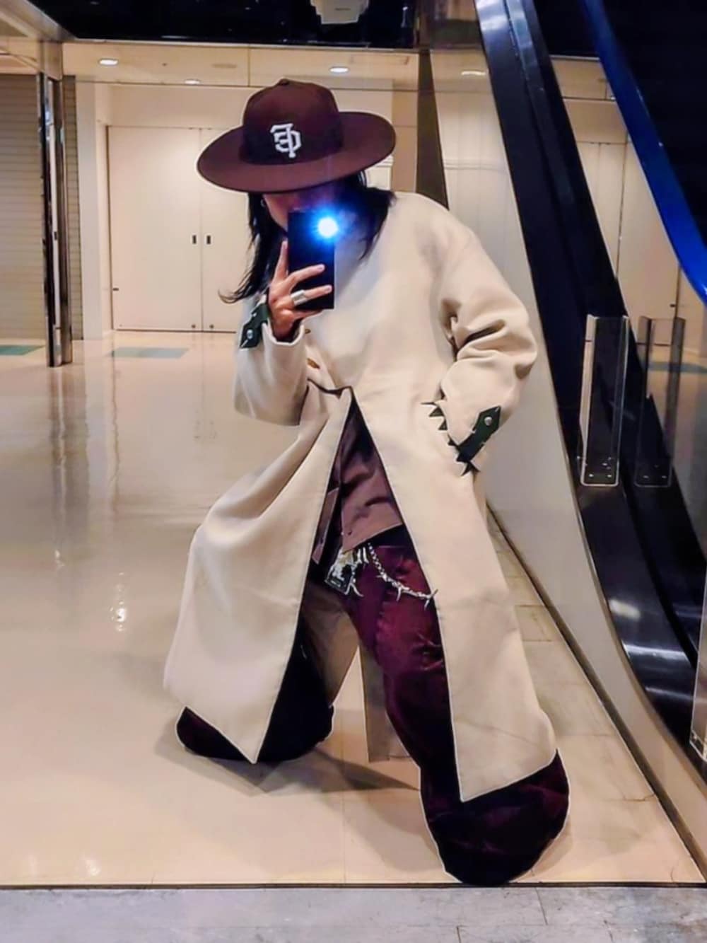 ベージュ系のノーカラーコート、ピンク系のデニムパンツ、ブラック系のブーツを着用したメンズの春コーディネートの4枚目の写真