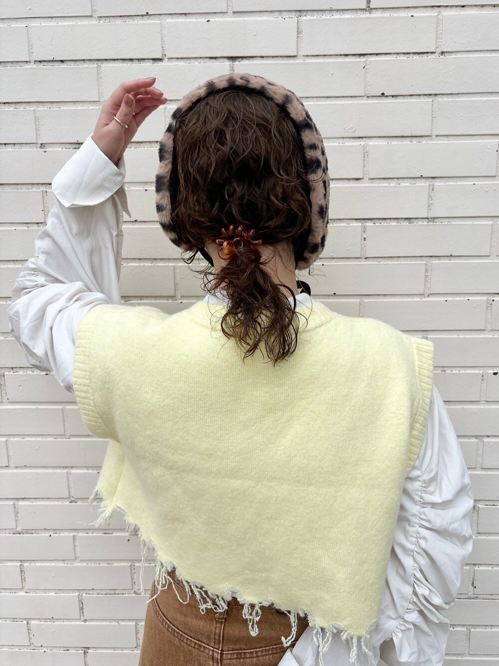 イエロー系のベスト、ブラウン系のデニムスカート、ブラウン系のサンダルを着用したレディースの秋コーディネートの6枚目の写真