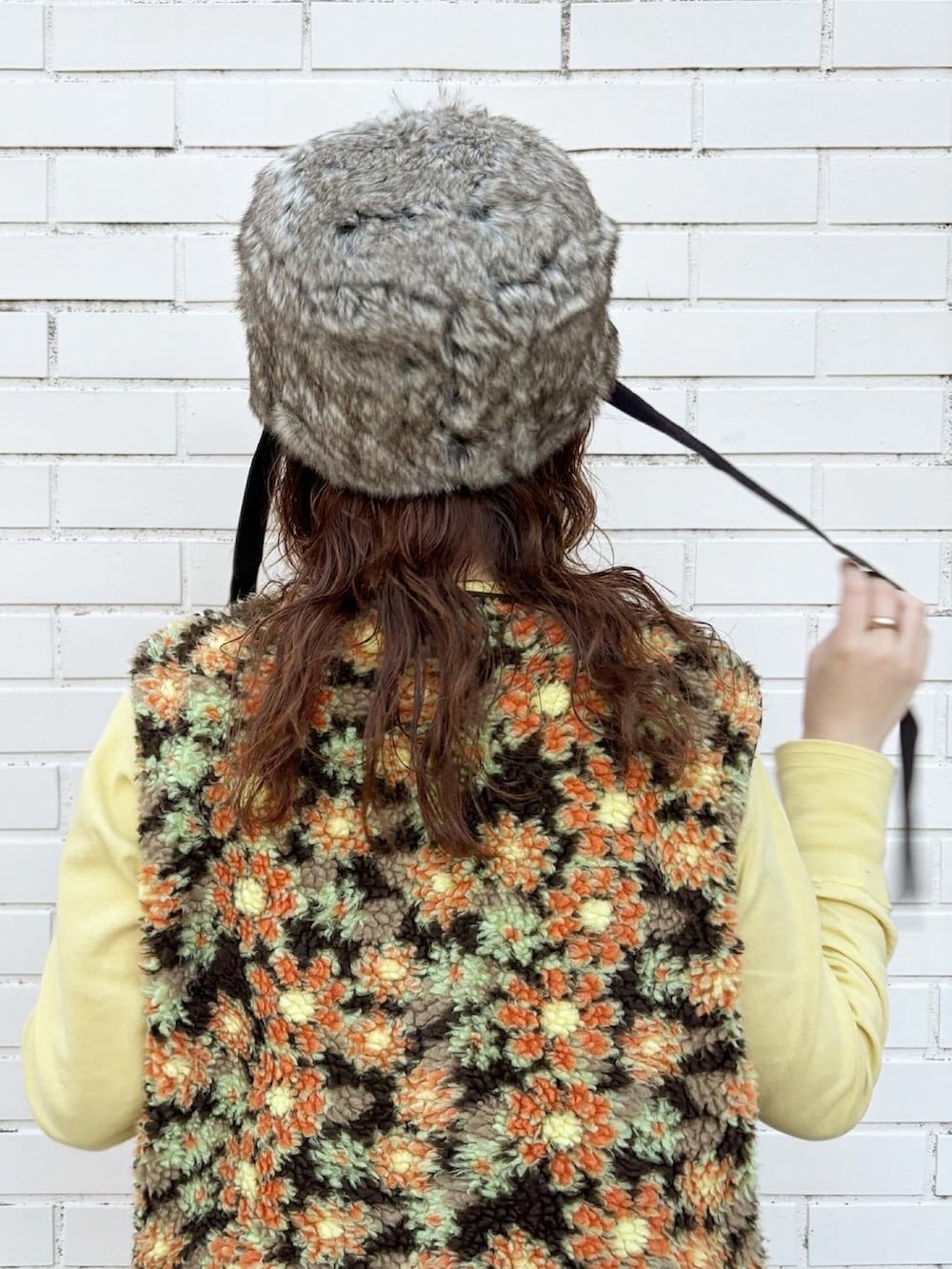 ベージュ系のベスト、イエロー系のTシャツ/カットソー、ブラウン系のデニムスカートを着用したレディースの秋コーディネートの3枚目の写真