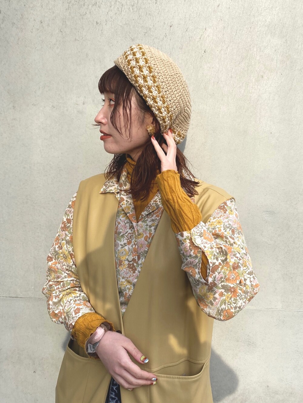 ベージュ系のベスト、イエロー系のシャツ/ブラウス、ブルー系のデニムパンツを着用したレディースの春コーディネートの2枚目の写真