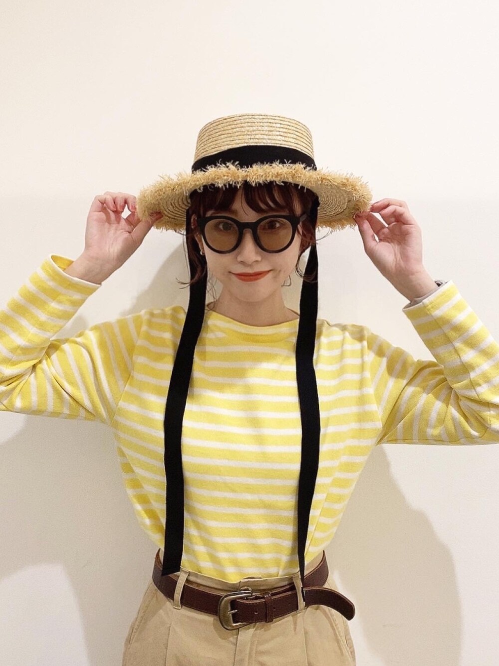 イエロー系のTシャツ/カットソー、ベージュ系のチノパンツ、ブラック系のバレエシューズを着用したレディースの春コーディネートの2枚目の写真