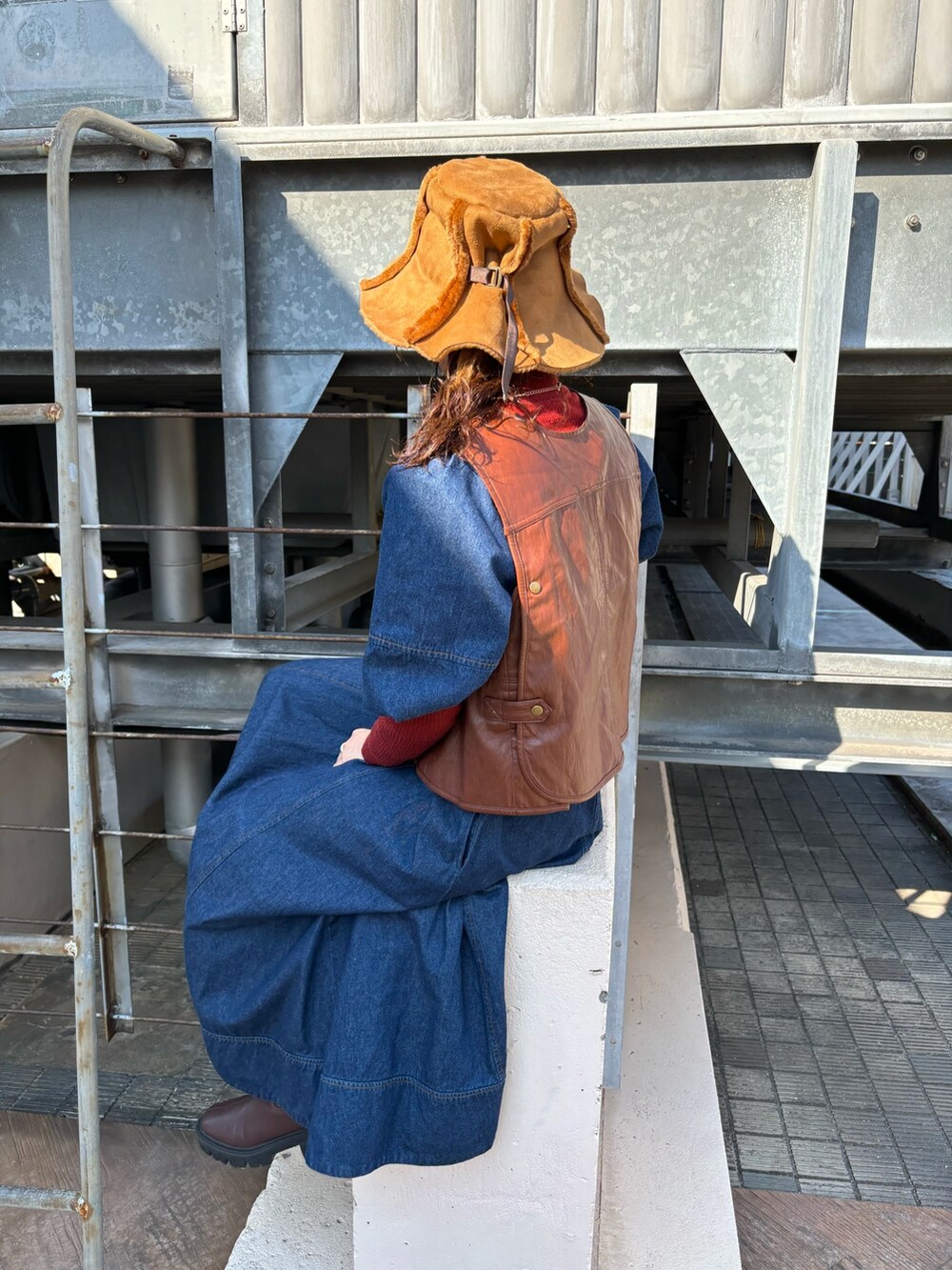 ブラウン系のベスト、ブルー系のワンピース、レッド系のトップスを着用したレディースの秋コーディネートの3枚目の写真