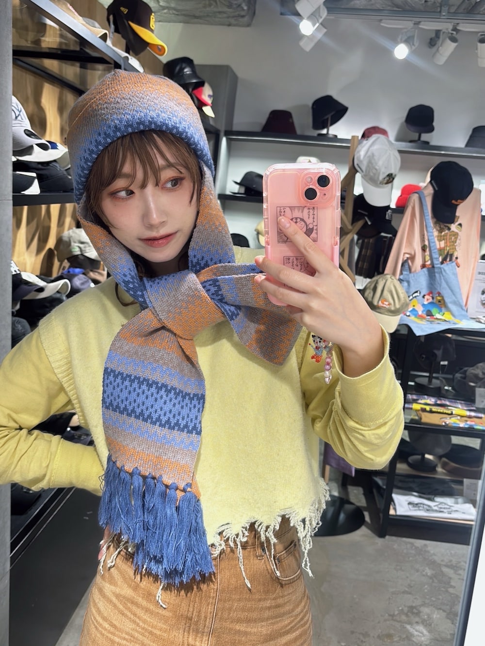 ブラウン系のデニムスカート、イエロー系のベスト、ベージュ系のスニーカーを着用したレディースの秋コーディネートの6枚目の写真