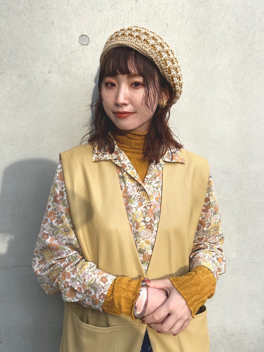 ベージュ系のベスト、イエロー系のシャツ/ブラウス、ブルー系のデニムパンツを着用したレディースの春コーディネートの3枚目の写真