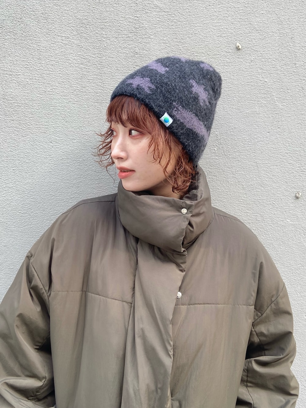 グリーン系のダウンジャケット/コート、グレー系のパンツ、ブラウン系のモカシン/デッキシューズを着用したレディースの冬コーディネートの6枚目の写真