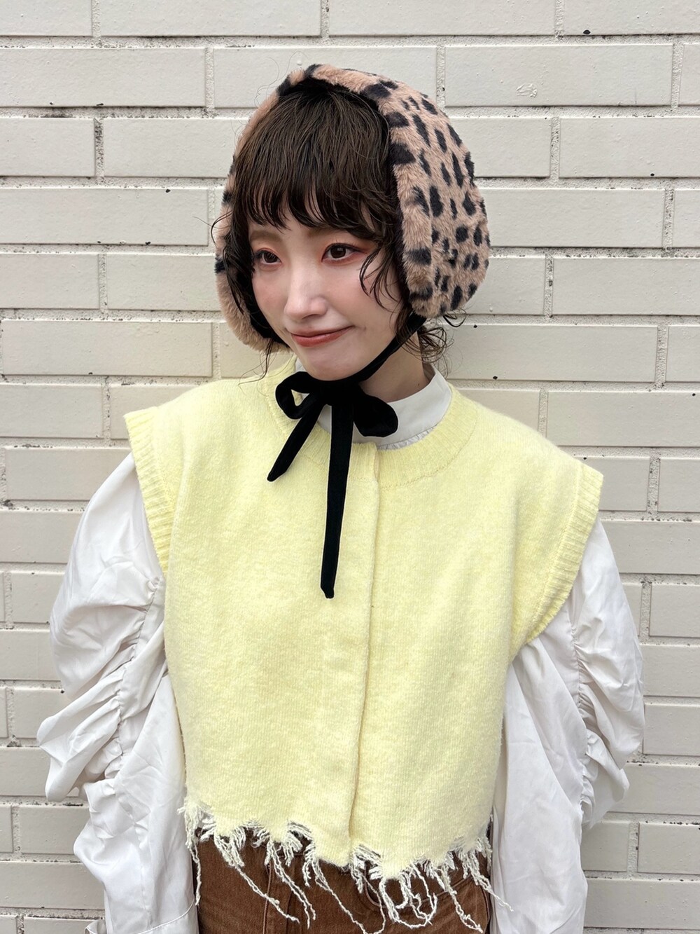 イエロー系のベスト、ブラウン系のデニムスカート、ブラウン系のサンダルを着用したレディースの秋コーディネートの2枚目の写真