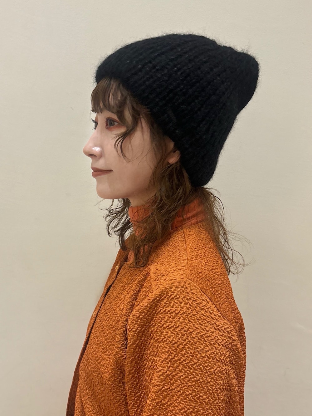 オレンジ系のカーディガン/ボレロ、ブラック系のスリッポン、ブラック系のニットキャップ/ビーニーを着用したレディースの秋コーディネートの2枚目の写真