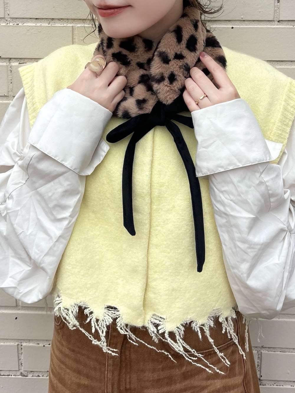 イエロー系のベスト、ブラウン系のデニムスカート、ブラウン系のサンダルを着用したレディースの秋コーディネートの5枚目の写真