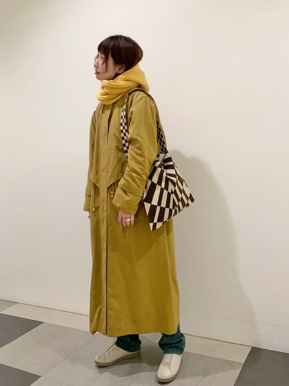 イエロー系のジャケット/アウター、ベージュ系のショルダーバッグ、グレー系のスニーカーを着用したレディースの冬コーディネートの2枚目の写真