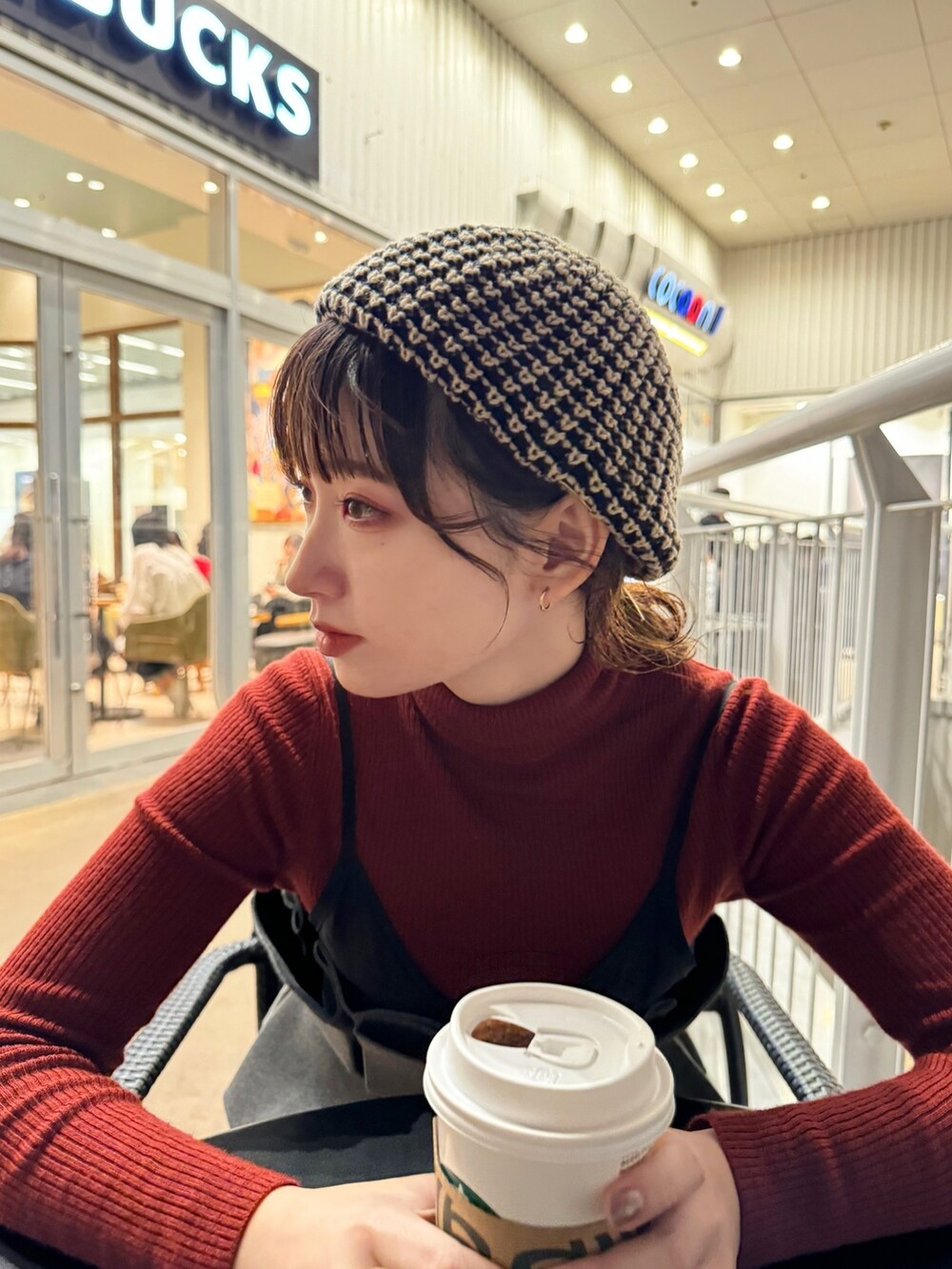 レッド系のトップス、グレー系のキャミソール、ブラック系のスウェットパンツを着用したレディースの秋コーディネートの2枚目の写真