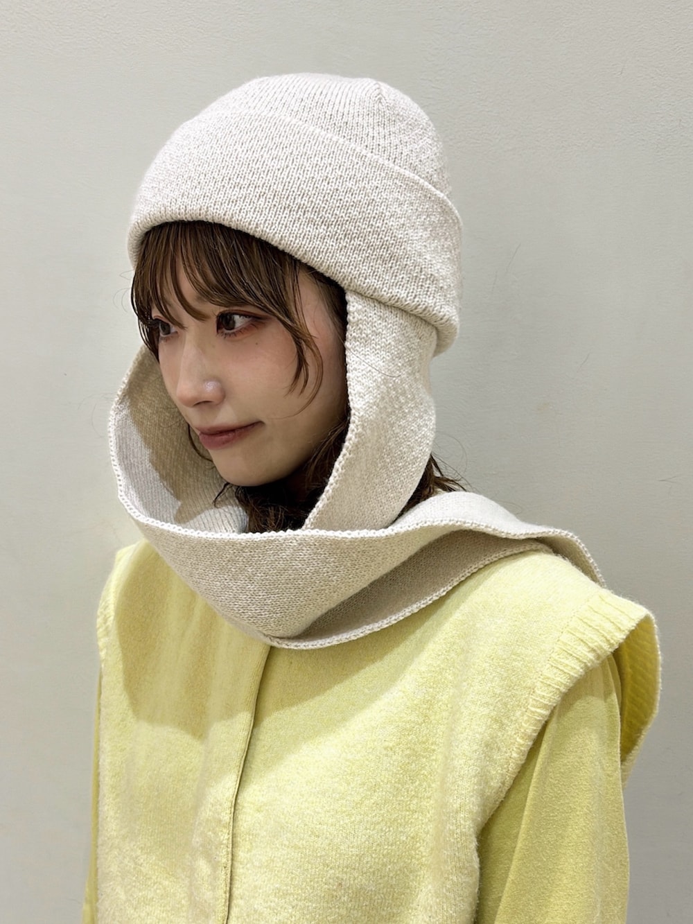 ブラウン系のデニムスカート、イエロー系のベスト、ベージュ系のスニーカーを着用したレディースの秋コーディネートの4枚目の写真