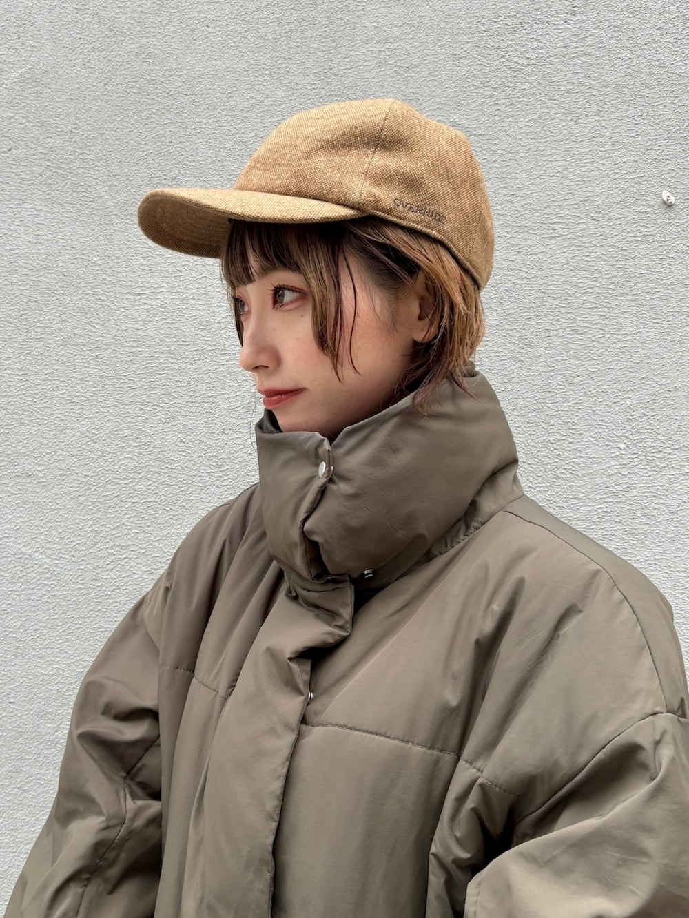 グリーン系のダウンジャケット/コート、ブラウン系のデニムスカート、ベージュ系のスニーカーを着用したレディースの秋コーディネートの3枚目の写真