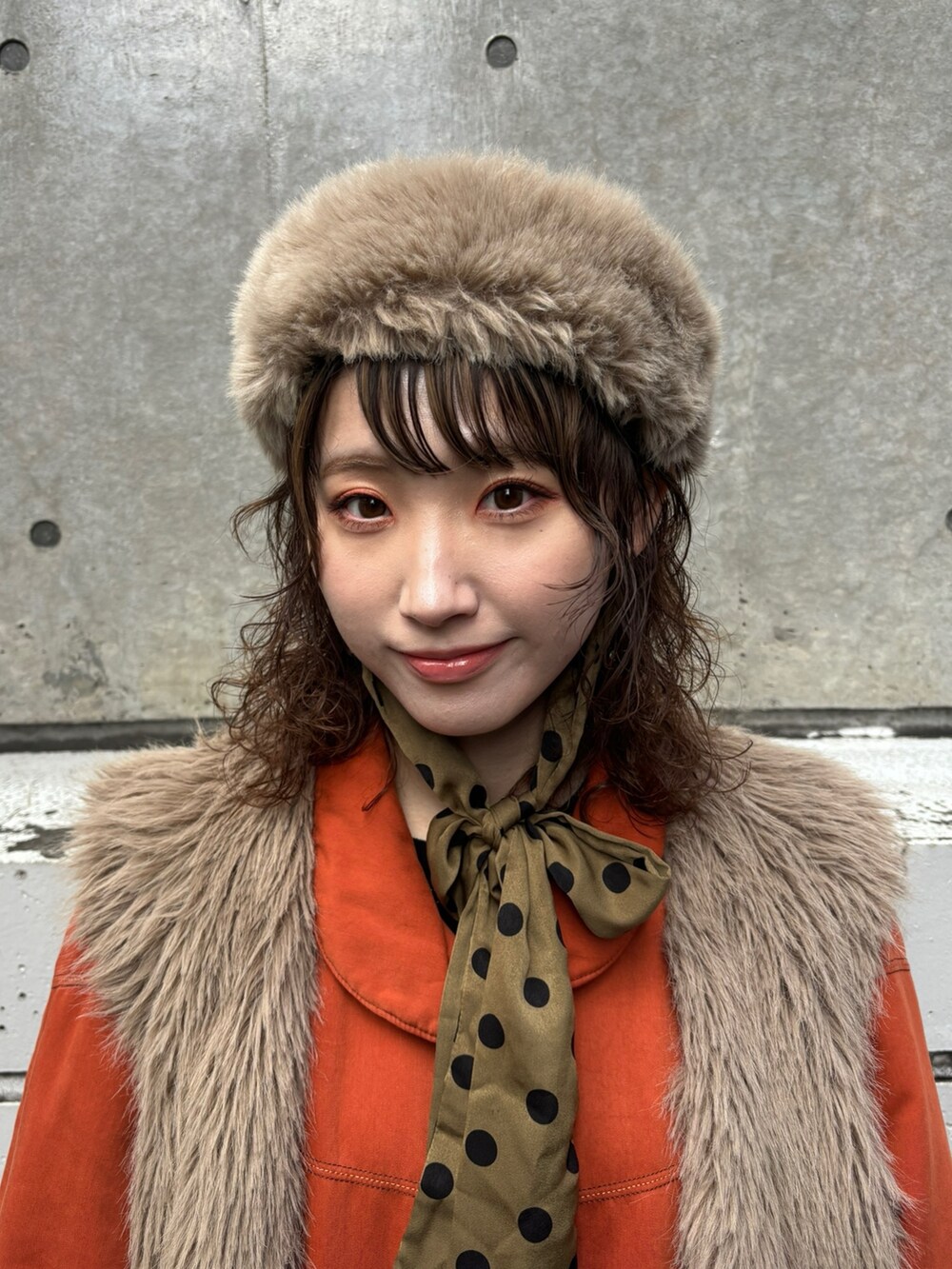 ベージュ系のベスト、オレンジ系のジャケット/アウター、ブラック系のワンピースを着用したレディースの春コーディネートの2枚目の写真