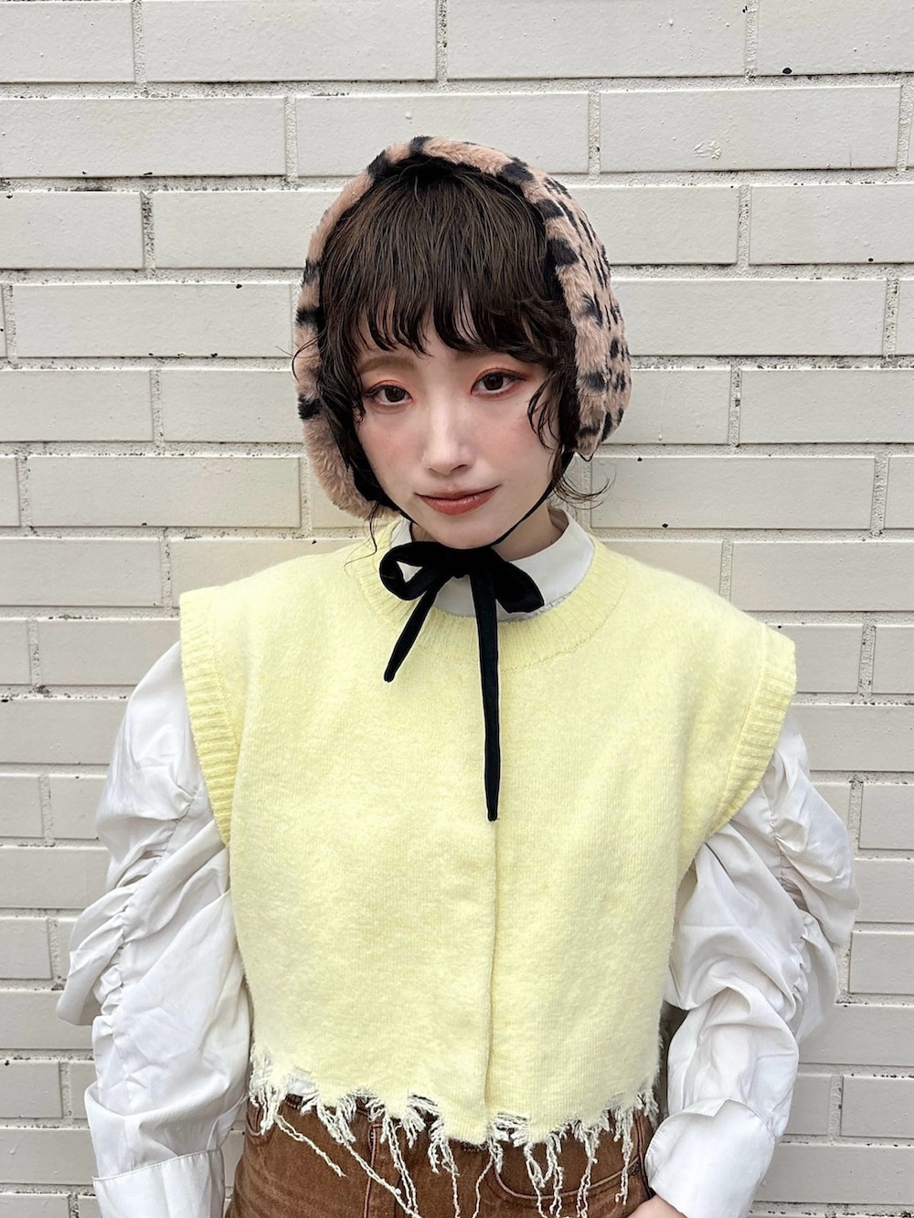 イエロー系のベスト、ブラウン系のデニムスカート、ブラウン系のサンダルを着用したレディースの秋コーディネートの3枚目の写真