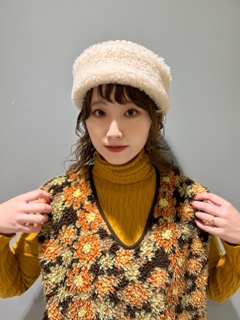 ベージュ系のベスト、ブラウン系のパンツ、イエロー系のスニーカーを着用したレディースの秋コーディネートの2枚目の写真