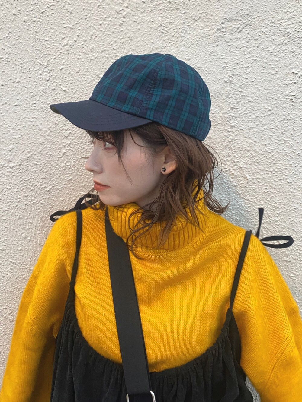 ブラック系のワンピース、ブラック系のブーツ、イエロー系のニット/セーターを着用したレディースの秋コーディネートの2枚目の写真