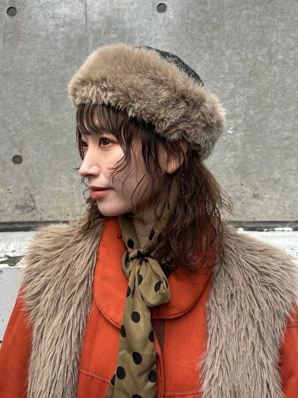 ベージュ系のベスト、オレンジ系のジャケット/アウター、ブラック系のワンピースを着用したレディースの春コーディネートの3枚目の写真