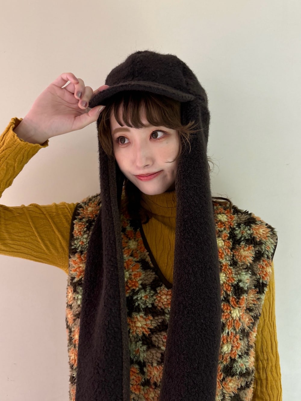 ベージュ系のベスト、ブラウン系のパンツ、イエロー系のスニーカーを着用したレディースの秋コーディネートの2枚目の写真