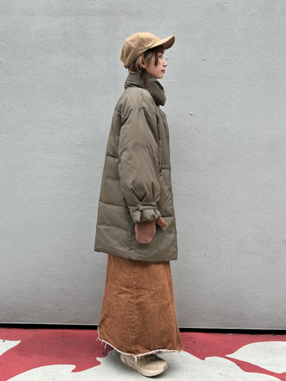 グリーン系のダウンジャケット/コート、ブラウン系のデニムスカート、ベージュ系のスニーカーを着用したレディースの秋コーディネートの2枚目の写真