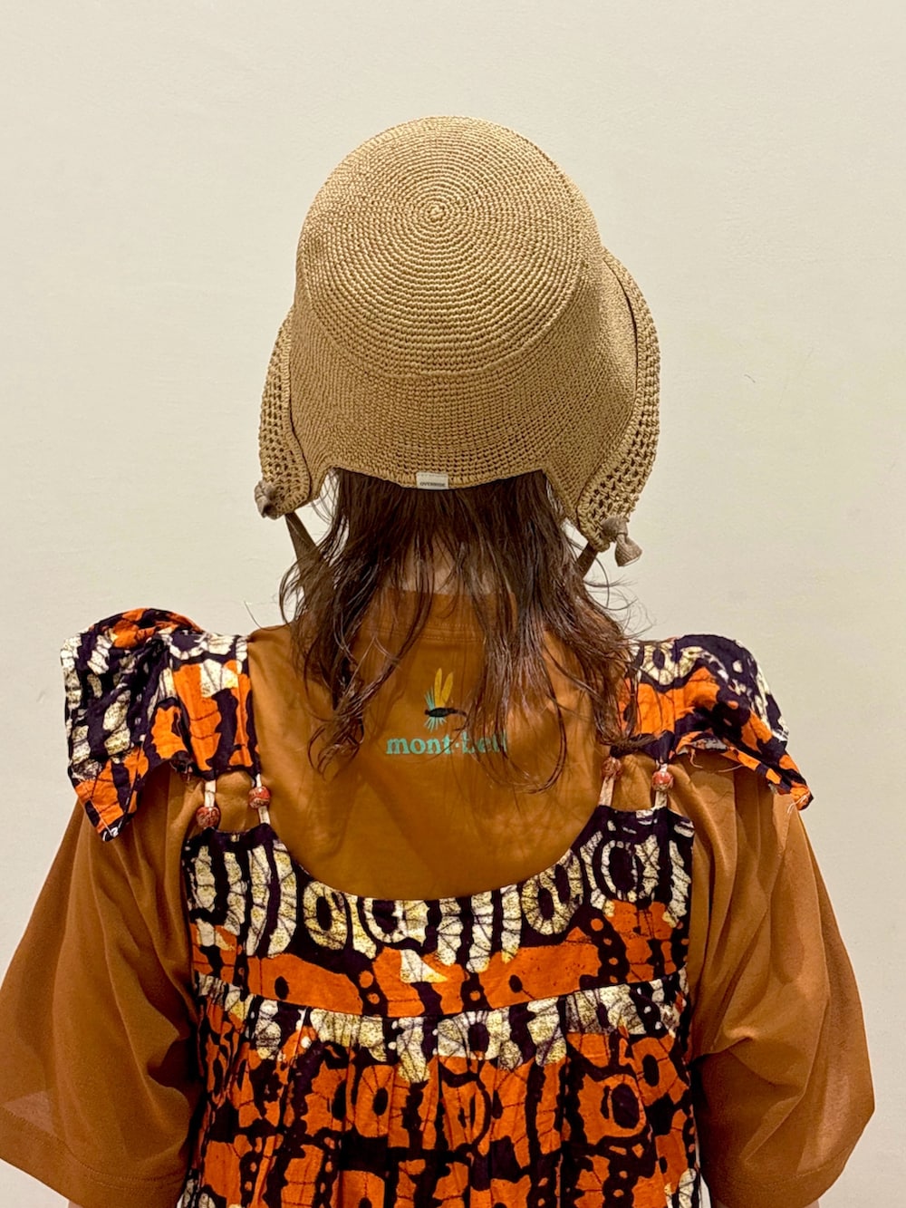 オレンジ系のワンピース/ドレス、ブラウン系のTシャツ/カットソー、ベージュ系のスニーカーを着用したレディースの夏コーディネートの3枚目の写真