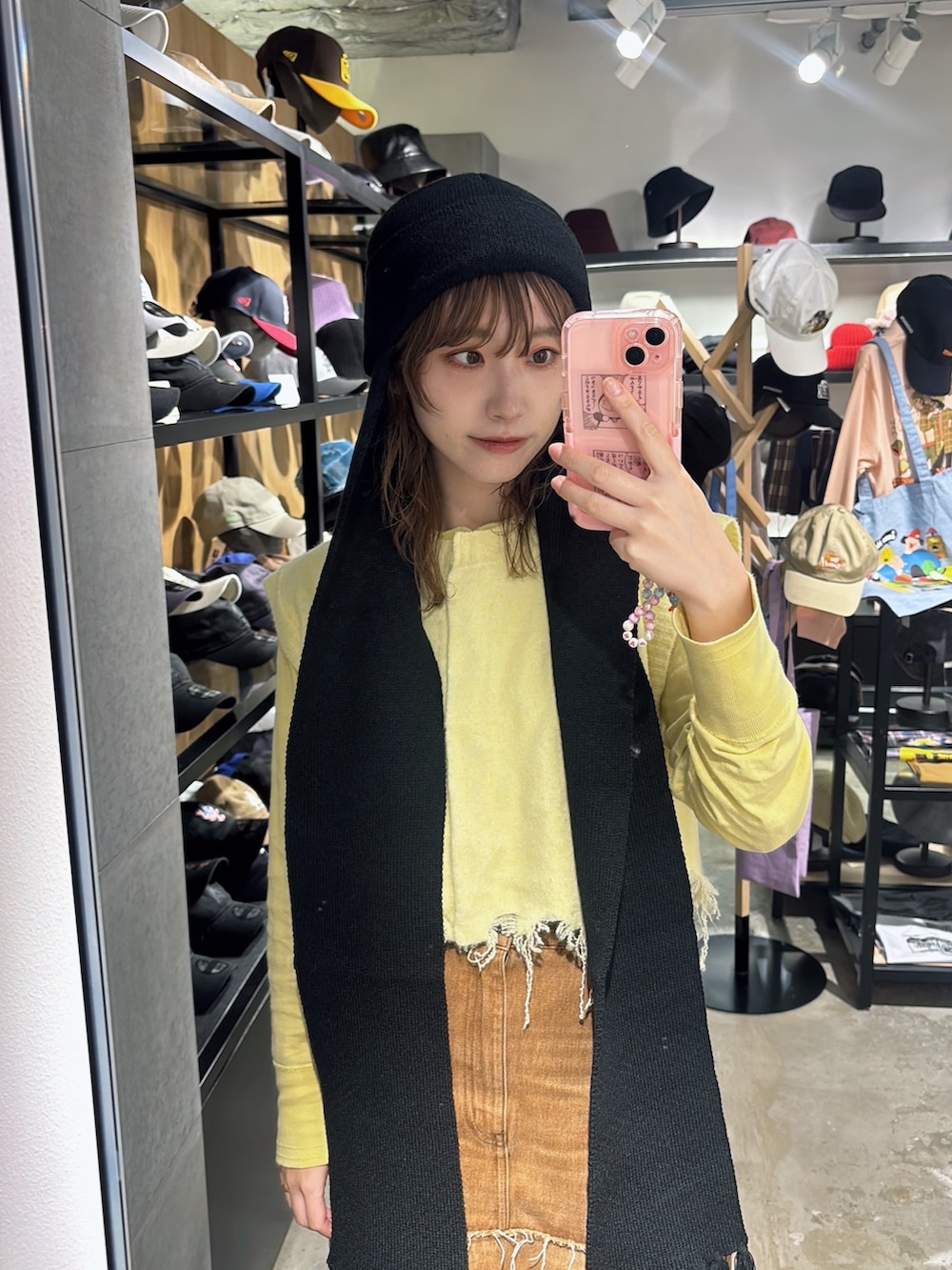 ブラウン系のデニムスカート、イエロー系のベスト、ベージュ系のスニーカーを着用したレディースの秋コーディネートの7枚目の写真