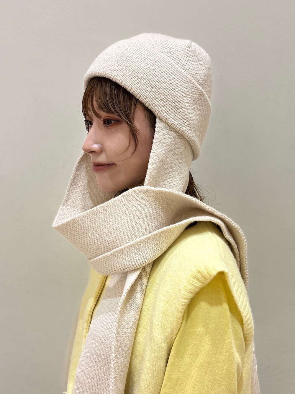 ブラウン系のデニムスカート、イエロー系のベスト、ベージュ系のスニーカーを着用したレディースの秋コーディネートの3枚目の写真