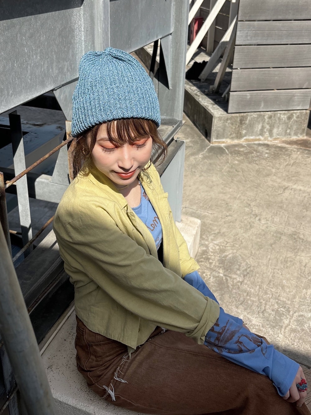 グリーン系のジャケット/アウター、ブラウン系のデニムスカート、ベージュ系のスニーカーを着用したレディースの春コーディネートの2枚目の写真