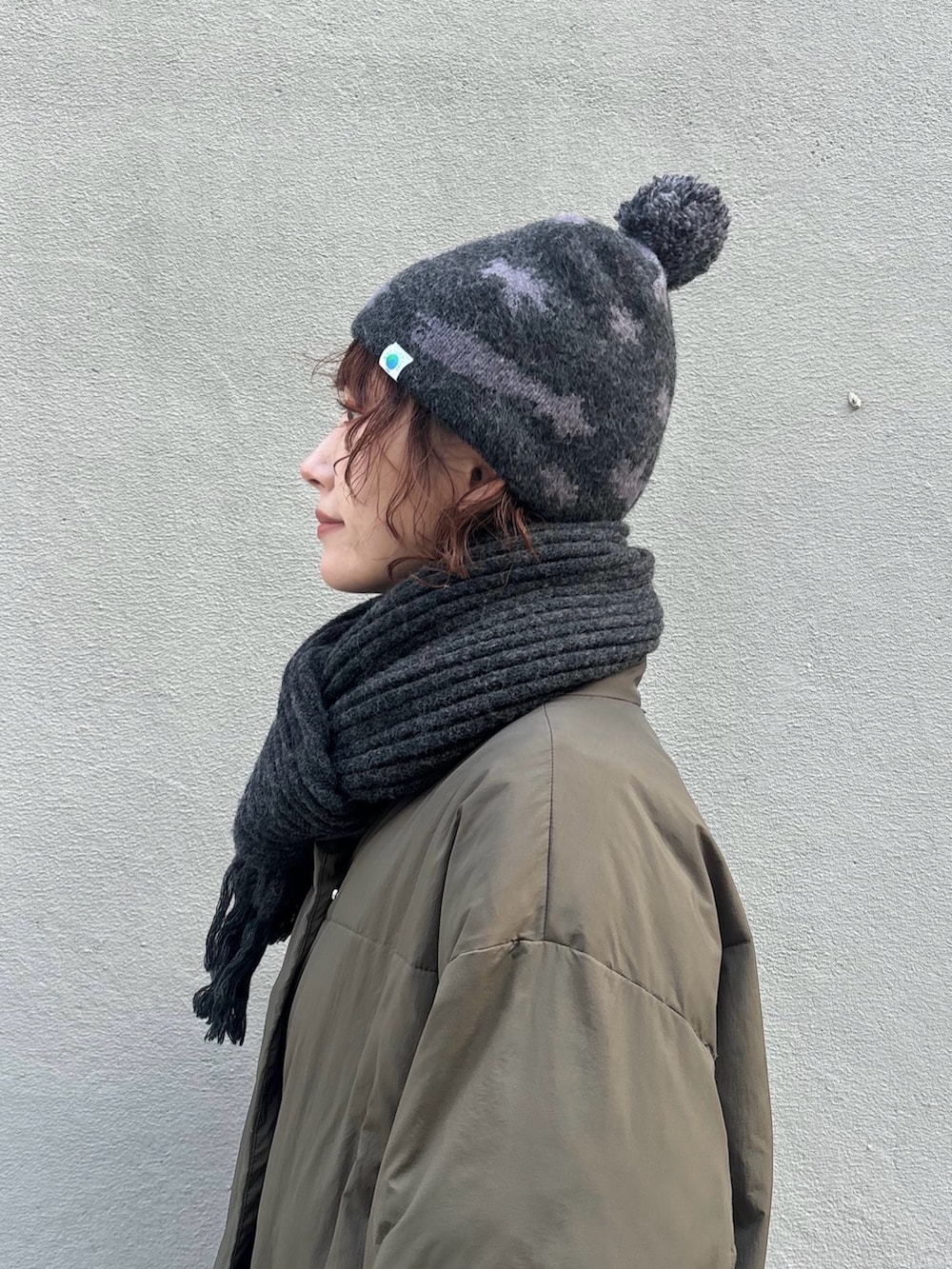 グリーン系のダウンジャケット/コート、グレー系のパンツ、ブラウン系のモカシン/デッキシューズを着用したレディースの冬コーディネートの5枚目の写真