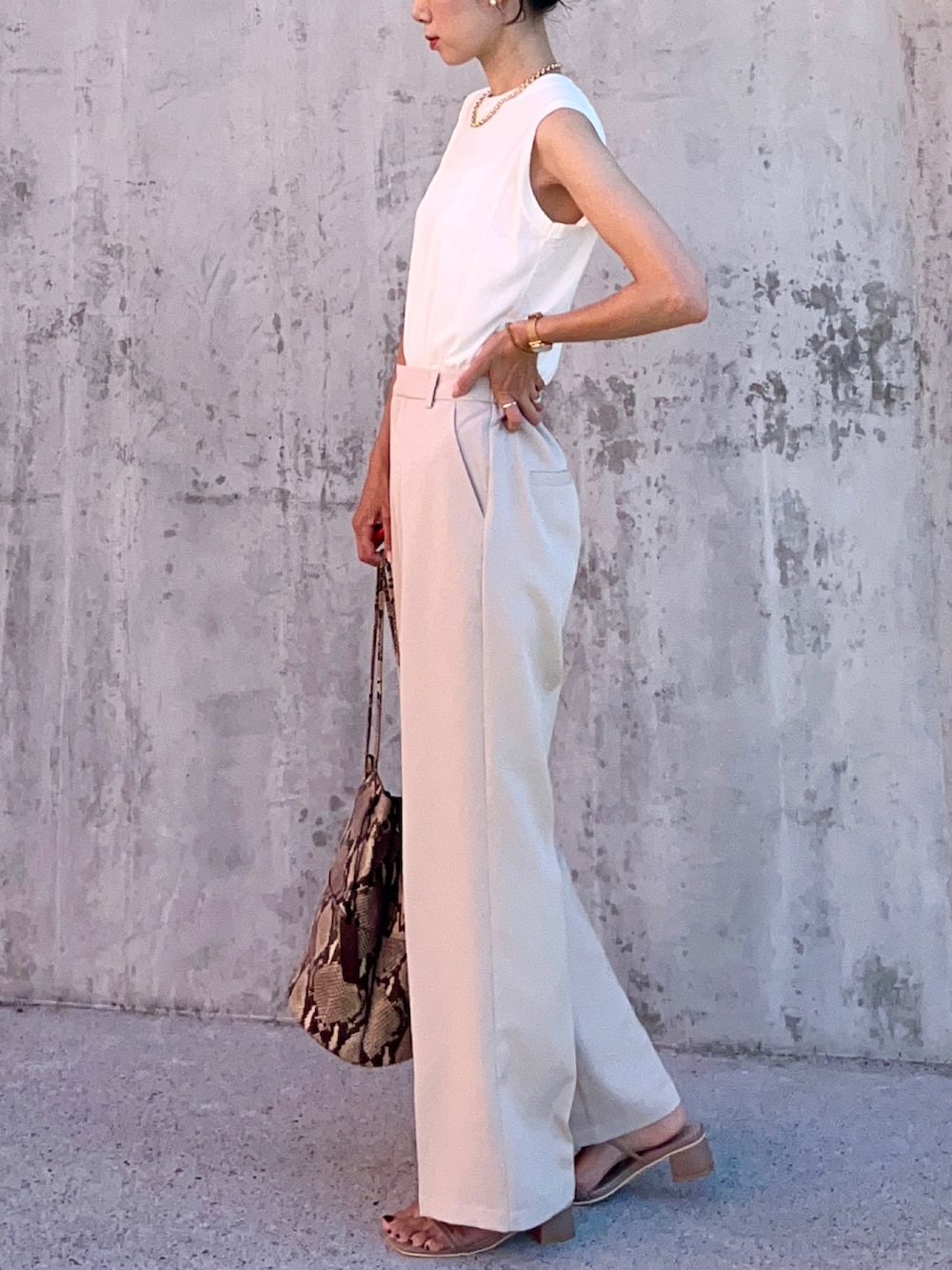 ホワイト系のTシャツ/カットソー、ホワイト系のスラックス、ベージュ系のサンダルを着用したレディースの夏コーディネートの3枚目の写真