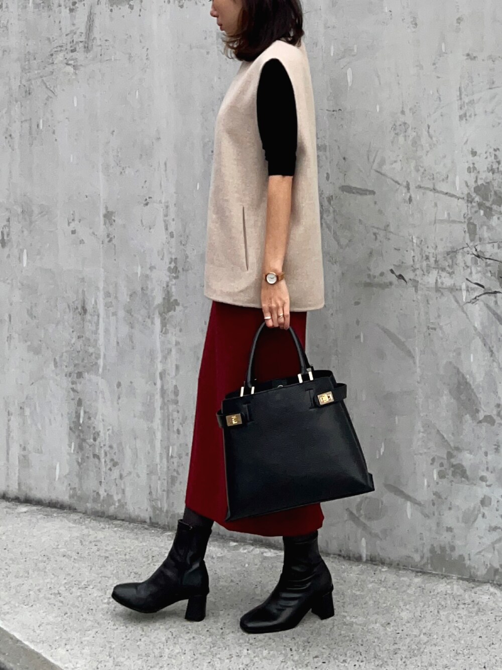 ブラック系のニット/セーター、ベージュ系のベスト、レッド系のスカートを着用したレディースの冬コーディネートの3枚目の写真