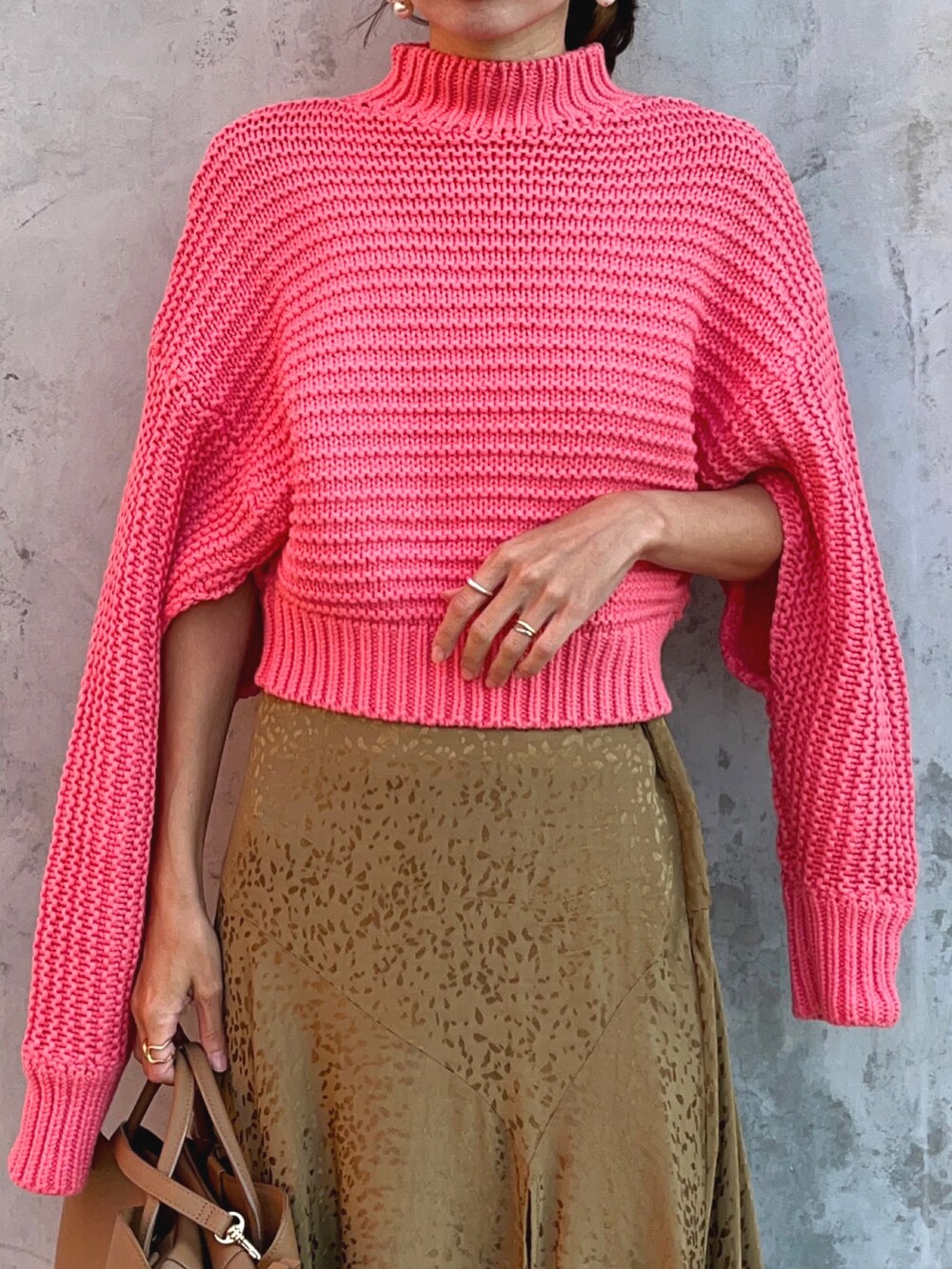 ピンク系のニット/セーター、ベージュ系のスカート、ブラウン系のブーツを着用したレディースの秋コーディネートの4枚目の写真