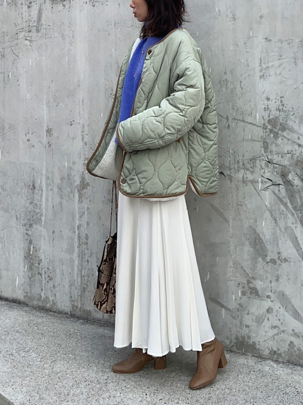 ブルー系のニット/セーター、ホワイト系のスカート、ブラウン系のブーツを着用したレディースの冬コーディネートの5枚目の写真