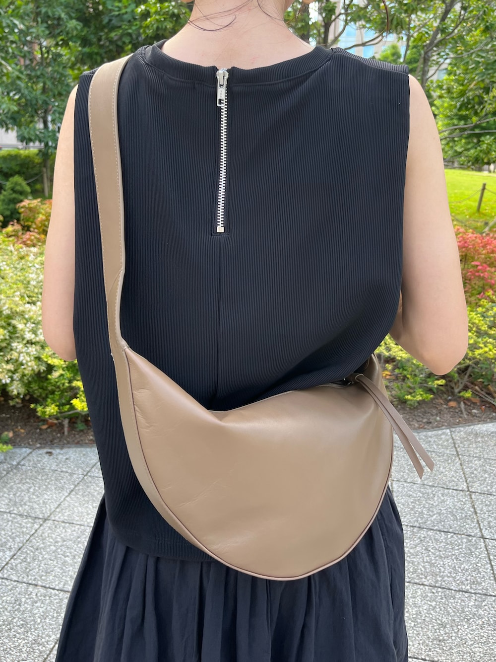 ブラック系のトップス、ブラック系のスカート、ブラウン系のサンダルを着用したレディースの夏コーディネートの2枚目の写真