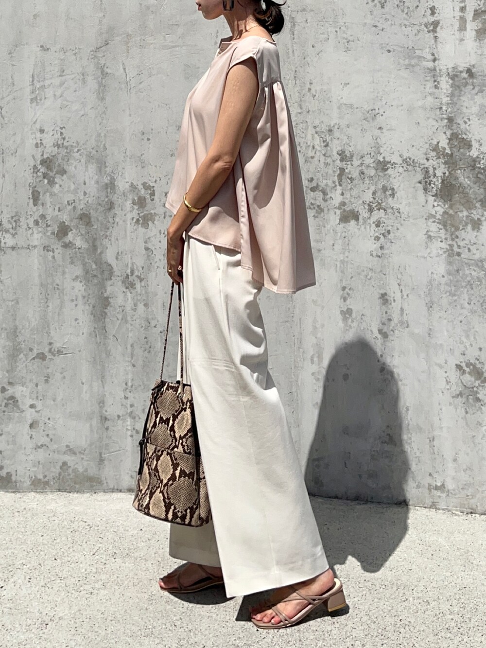 ホワイト系のシャツ/ブラウス、ホワイト系のパンツ、ベージュ系のサンダルを着用したレディースの夏コーディネートの3枚目の写真