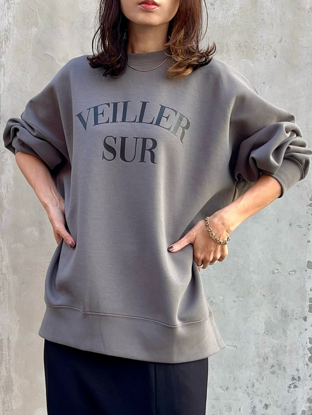 ブラック系のスカート、ブラック系のブーツ、ブラウン系のバッグを着用したレディースの秋コーディネートの2枚目の写真