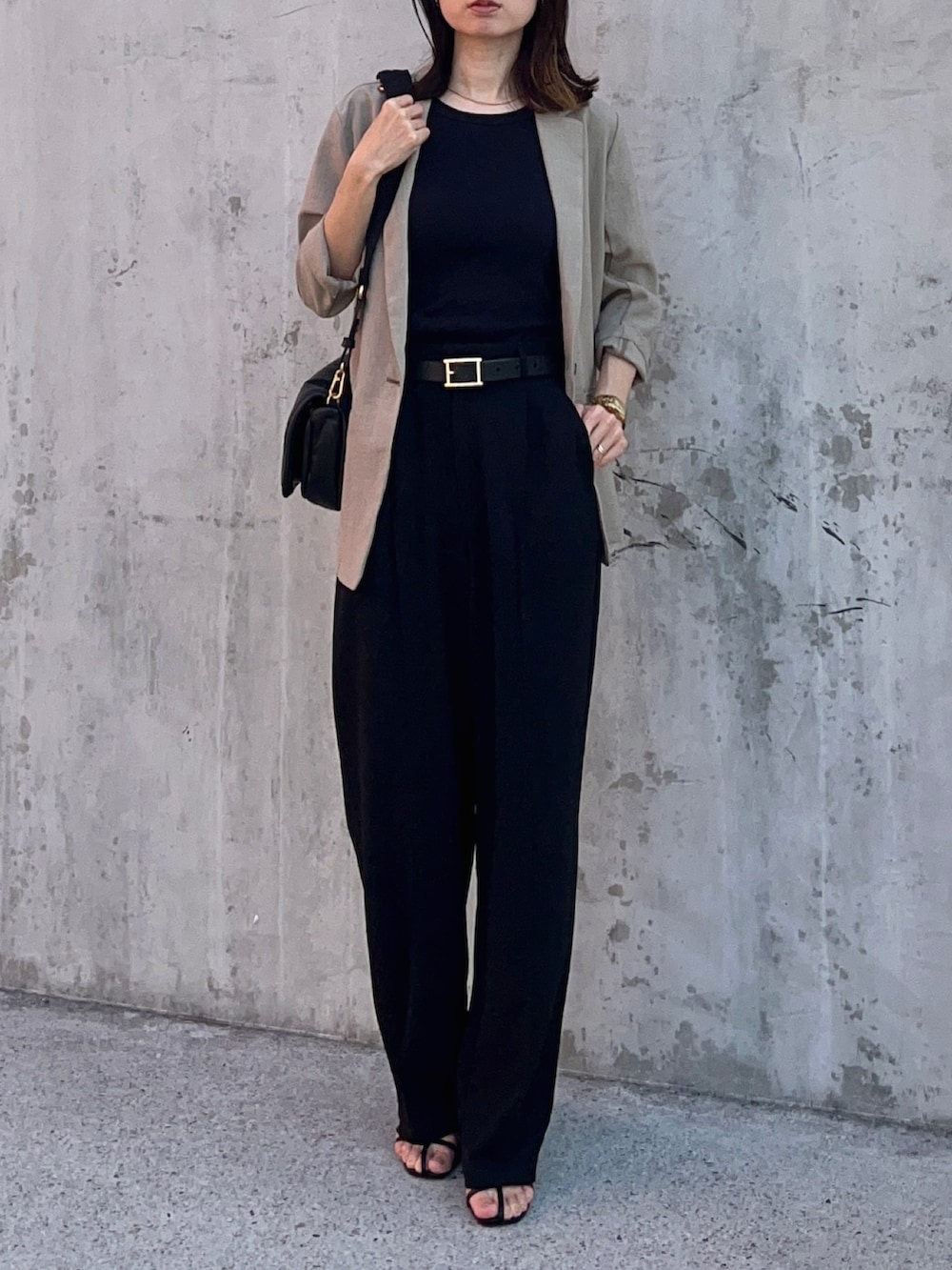 ブラック系のタンクトップ、グリーン系のテーラードジャケット、ブラック系のパンツを着用したレディースの春コーディネートの2枚目の写真