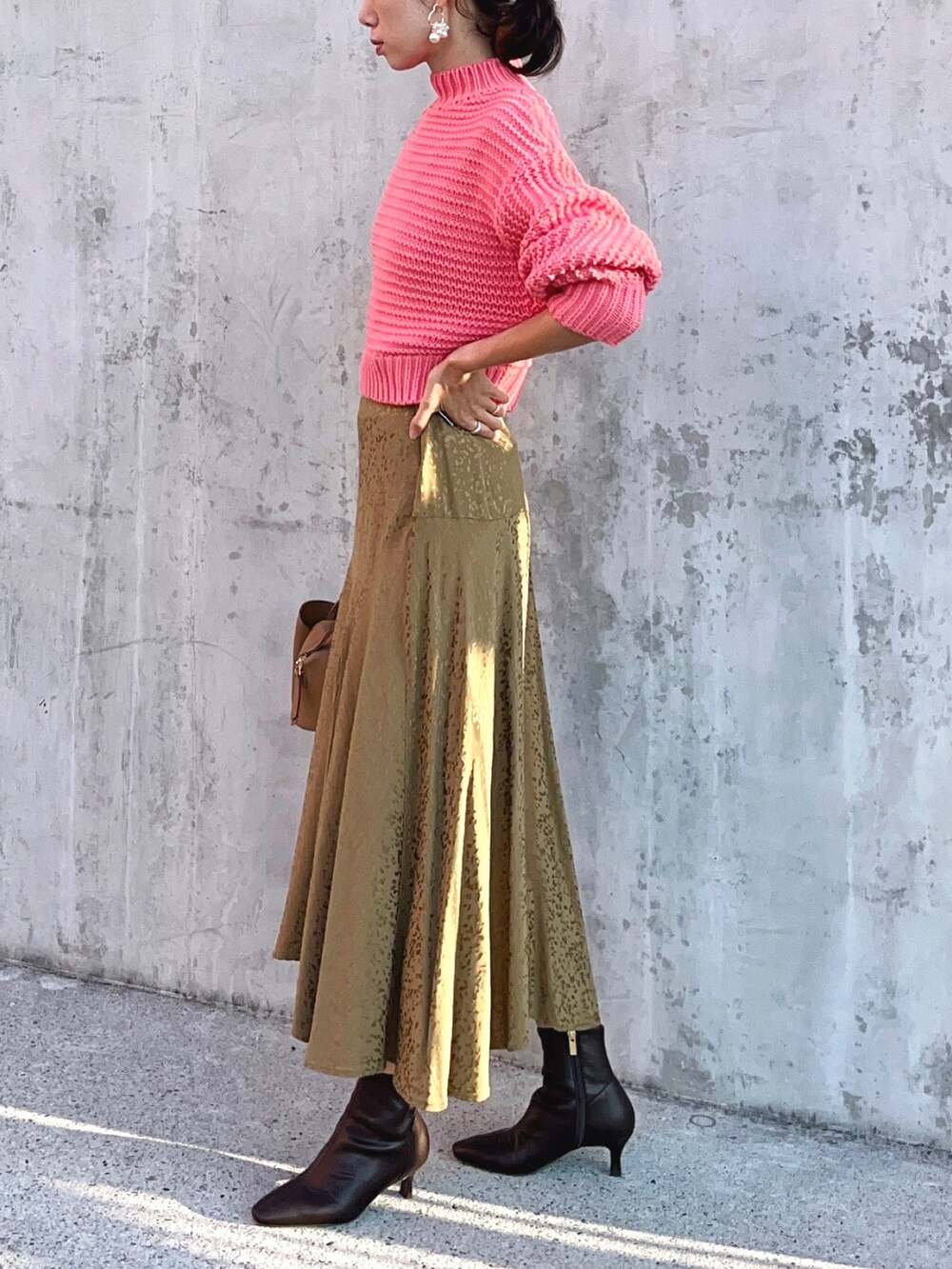 ピンク系のニット/セーター、ベージュ系のスカート、ブラウン系のブーツを着用したレディースの秋コーディネートの3枚目の写真