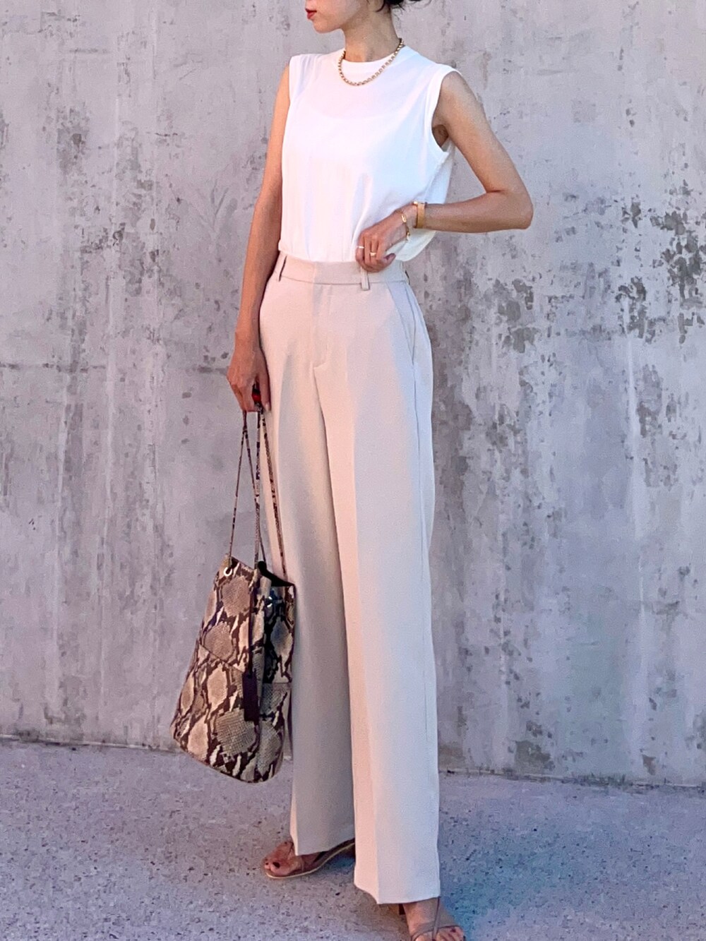 ホワイト系のTシャツ/カットソー、ホワイト系のスラックス、ベージュ系のサンダルを着用したレディースの夏コーディネートの4枚目の写真