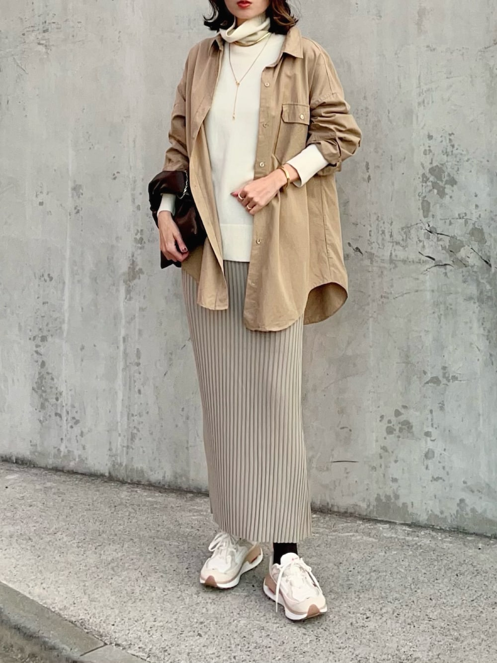 ホワイト系のニット/セーター、イエロー系のシャツ/ブラウス、ベージュ系のスカートを着用したレディースの冬コーディネートの2枚目の写真