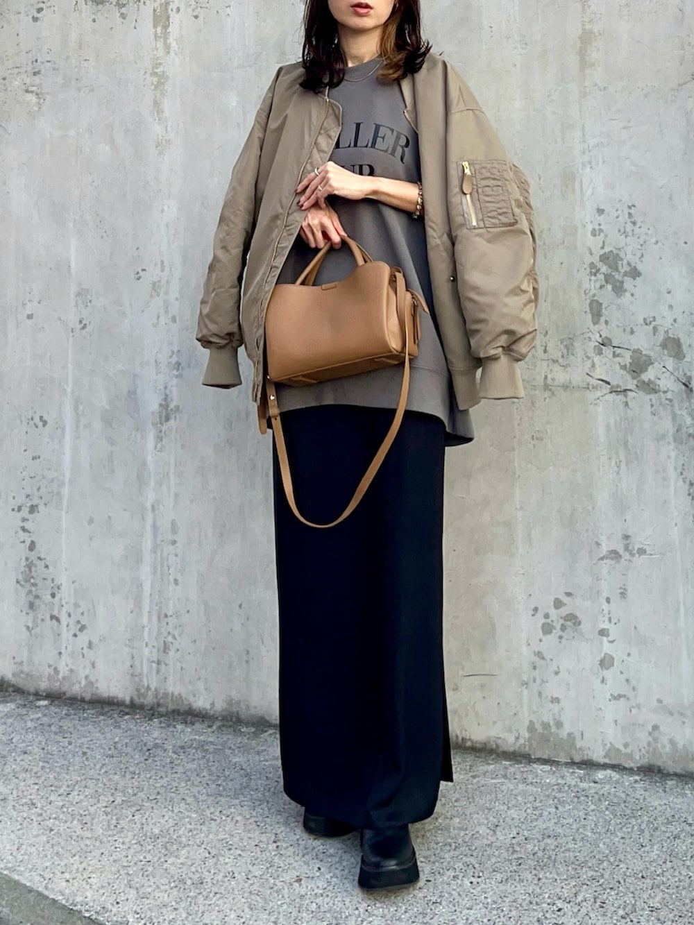 ブラック系のスカート、ブラック系のブーツ、ブラウン系のバッグを着用したレディースの秋コーディネートの3枚目の写真