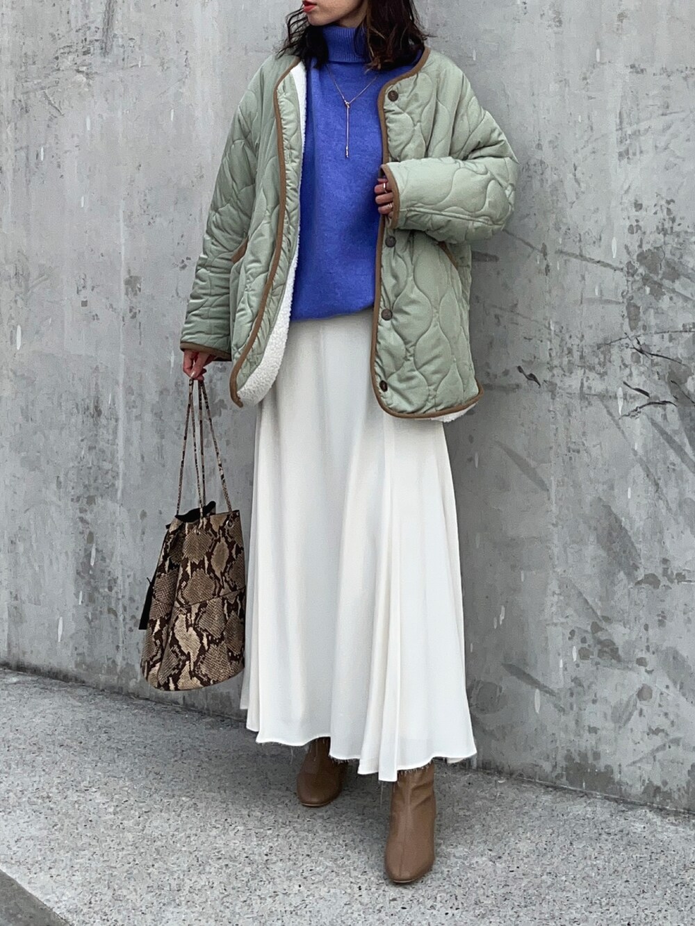 ブルー系のニット/セーター、ホワイト系のスカート、ブラウン系のブーツを着用したレディースの冬コーディネートの4枚目の写真