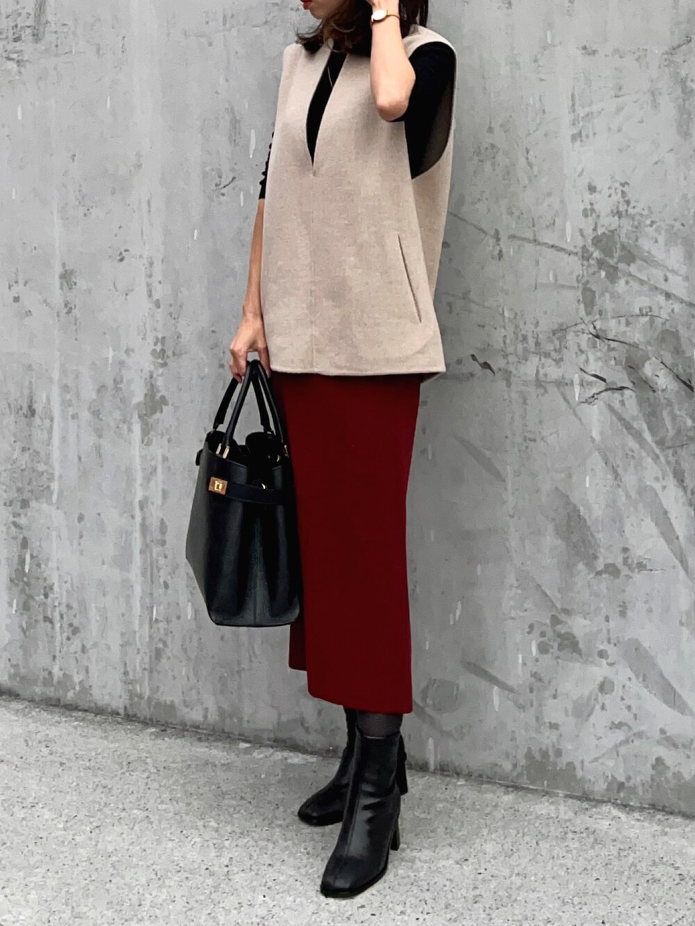 ブラック系のニット/セーター、ベージュ系のベスト、レッド系のスカートを着用したレディースの冬コーディネートの2枚目の写真