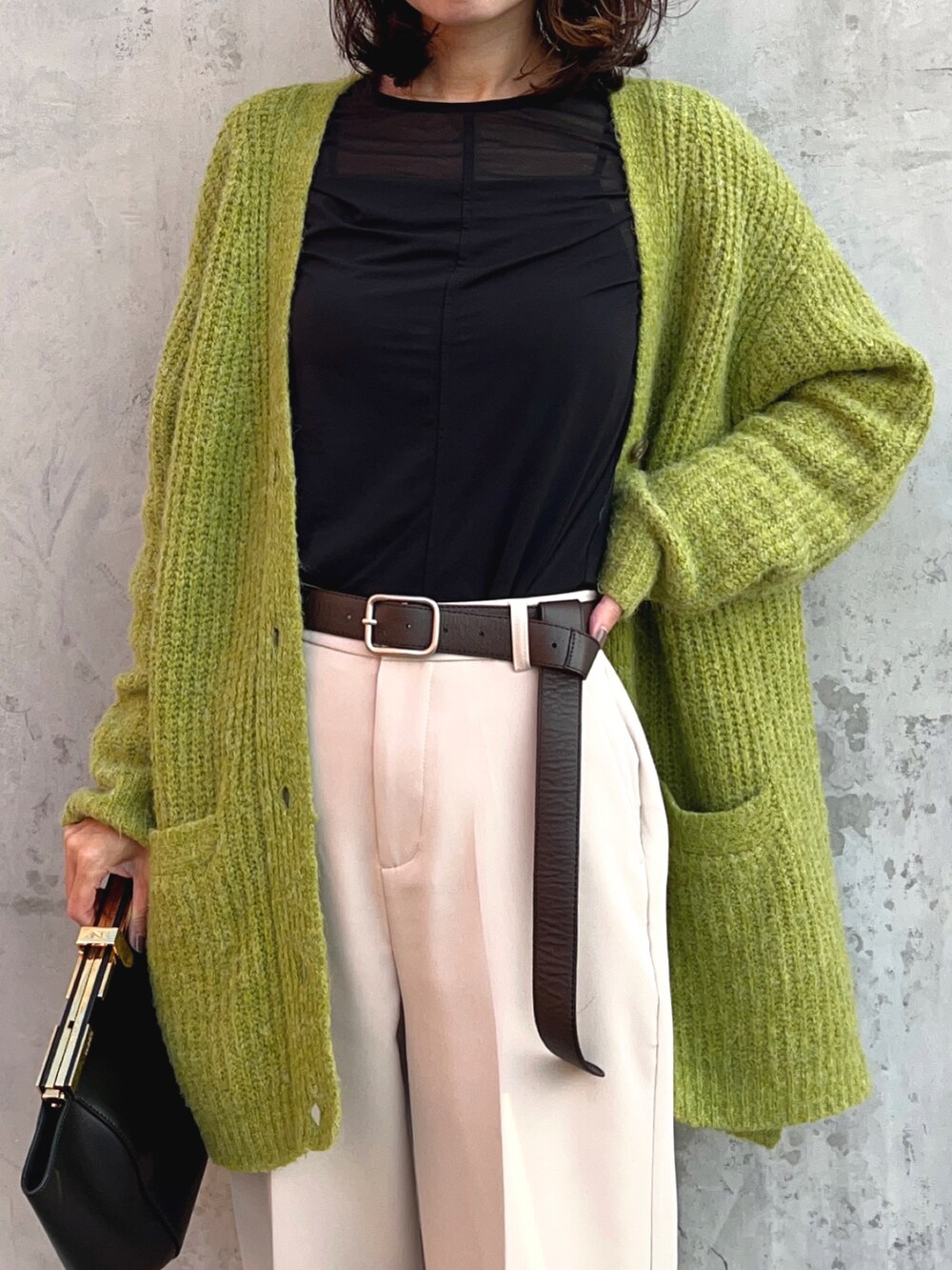 ブラック系のTシャツ/カットソー、グリーン系のカーディガン/ボレロ、ホワイト系のスラックスを着用したレディースの秋コーディネートの4枚目の写真