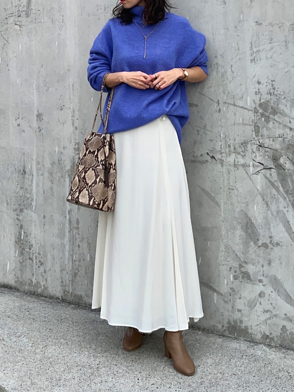 ブルー系のニット/セーター、ホワイト系のスカート、ブラウン系のブーツを着用したレディースの冬コーディネートの2枚目の写真