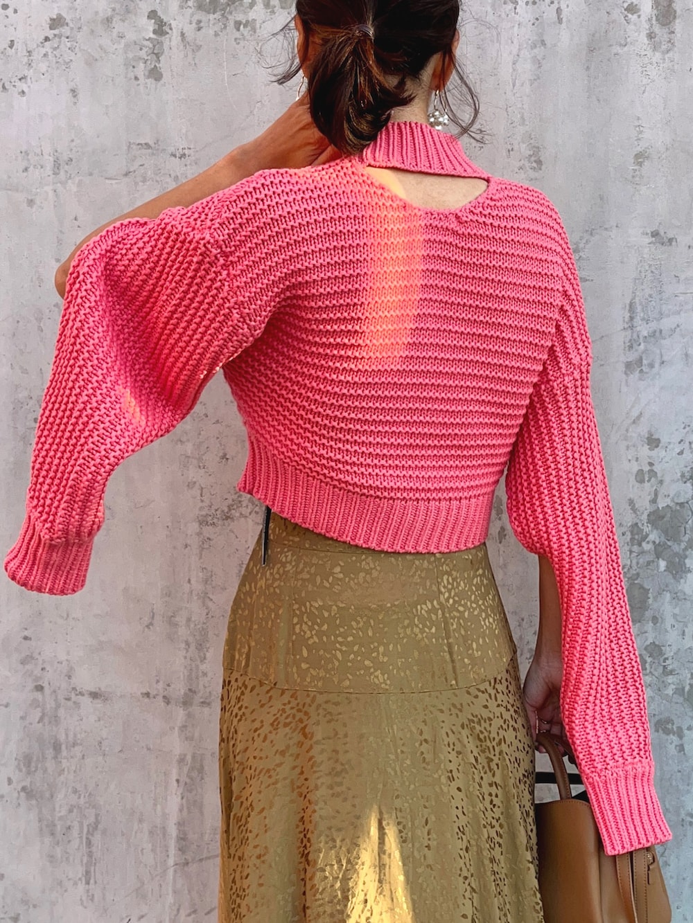 ピンク系のニット/セーター、ベージュ系のスカート、ブラウン系のブーツを着用したレディースの秋コーディネートの5枚目の写真