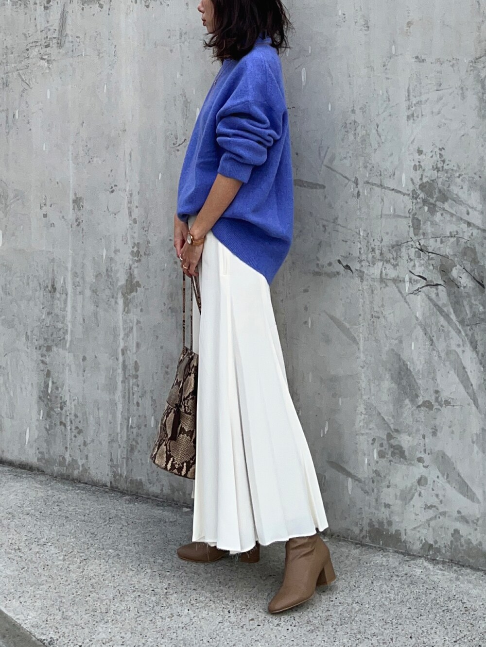 ブルー系のニット/セーター、ホワイト系のスカート、ブラウン系のブーツを着用したレディースの冬コーディネートの3枚目の写真