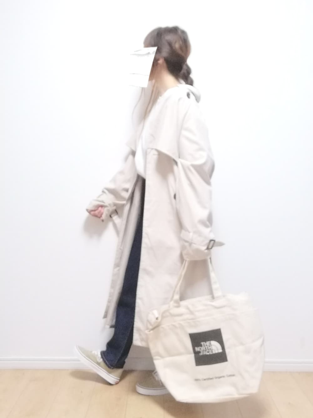 ホワイト系のトレンチコート、ブルー系のデニムパンツ、その他のトートバッグを着用したレディースの冬コーディネートの2枚目の写真