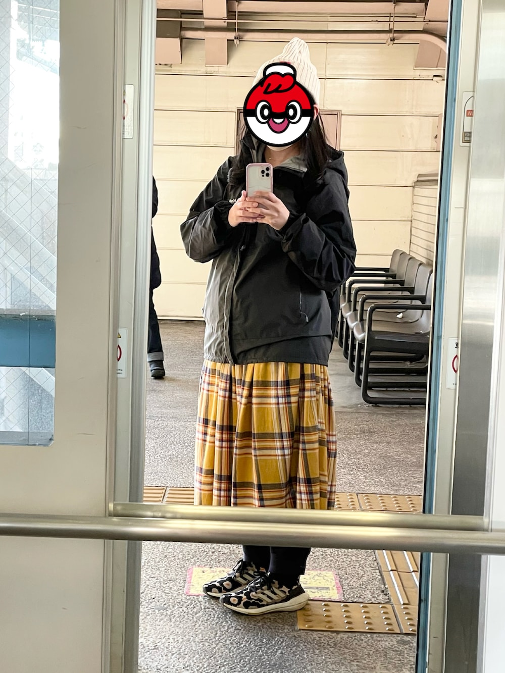 ブラック系のマウンテンパーカー、イエロー系のワンピース、ピンク系のスニーカーを着用したレディースの冬コーディネートの2枚目の写真