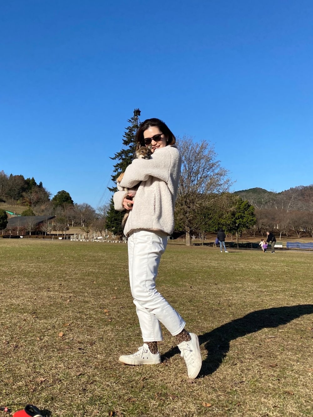 ベージュ系のトップス、ホワイト系のデニムパンツ、ホワイト系のスニーカーを着用したレディースの冬コーディネートの2枚目の写真